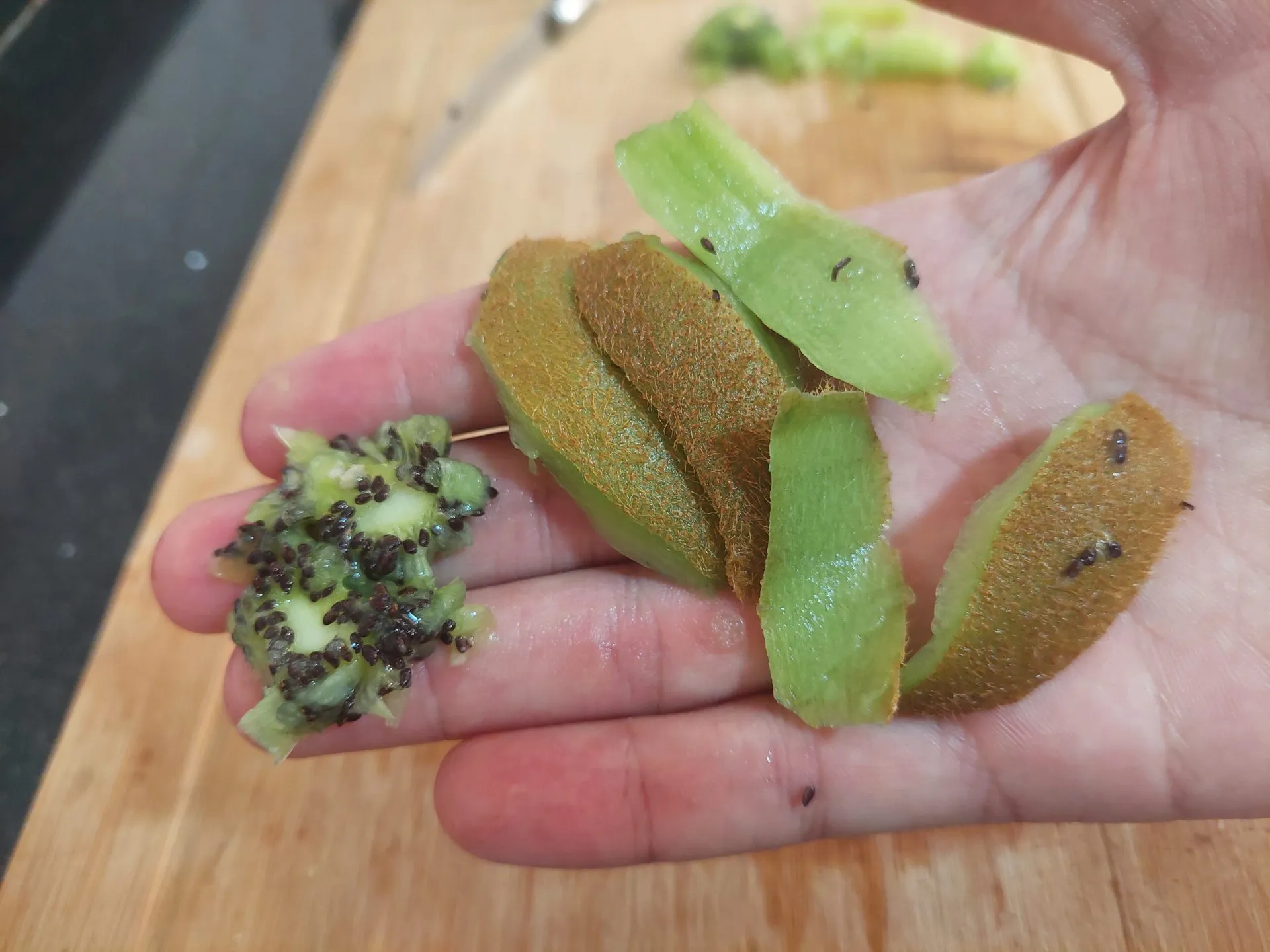 kiwi seeds and kiwi skin on a man's hand